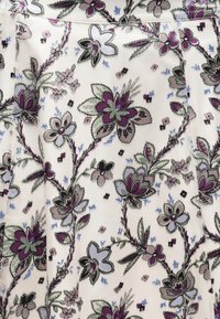 Lilleline kangas, kus on lilla, roheline ja sinine lilled kreemjal taustal. Sisaldab keerukat õmblust ja mitmekesiseid lehemustreid.