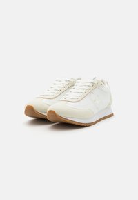 Hvite sneakers med en kombinasjon av lær og semsket skinn, med en teksturert gummisåle, snørelukking og subtile merkemerker.