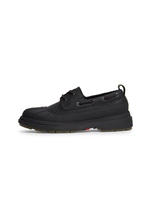 Chaussure imperméable noire basse avec lacets à l'avant, semelle en caoutchouc et languette au talon, vue de profil sur fond blanc.
