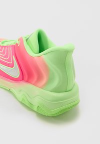 Scarpa sportiva neon rosa e verde con una tomaia texturizzata, tacco curvo e un logo argento visibile. Tessuto liscio con un design a strati.