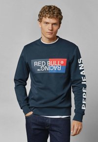 Sudadera azul marino con un gráfico audaz de "RED BULL RACING" en la parte frontal y "PEPE JEANS" impreso en la manga. Textura suave, cuello redondo.