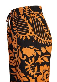 Zwarte en oranje gestreepte broek met een touwsluiting in de taille. Bevat gedurfde bloem- en bladpatronen. Gemaakt van lichte, gestructureerde stof.