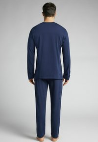 Námořnická modrá dlouhá mikina a odpovídající kalhoty vyrobené z měkké tkaniny, s jednoduchým designem bez viditelných vzorů nebo log.