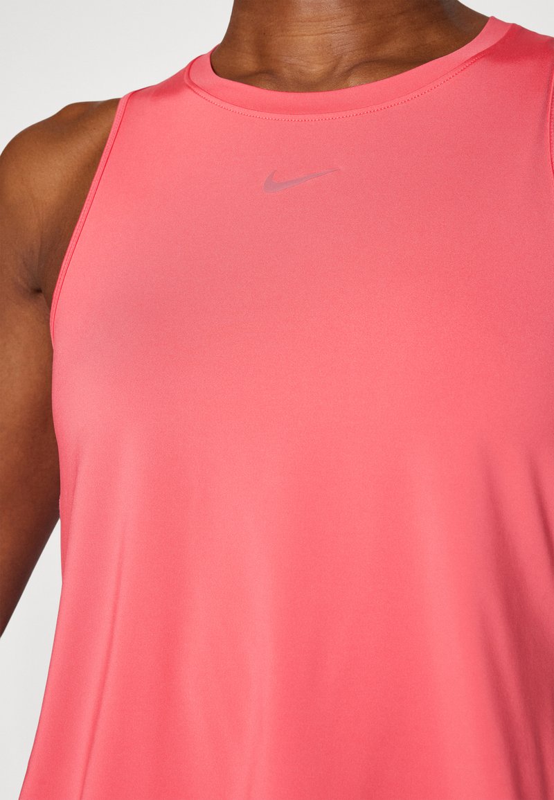 Top deportivo rosa hecho de una tela suave. Presenta un escote redondo y un pequeño logo plateado de Nike en el centro del frente.