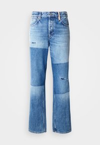 Blaue Jeans mit Schlag im Patchwork-Design, die hellere und dunklere Töne, abgenutzte Details und den traditionellen Fünf-Taschen-Stil aufweisen.