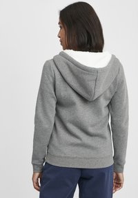Gray hoodie with white fleece lining in the hood, featuring a relaxed fit, long sleeves, and ribbed cuffs at the hem.