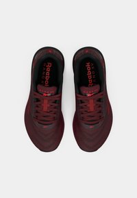 Reebok Nano XV-sneakers, röd och svart mesh-överk och, platta snören, vadderad krage, texturerad sula, logotyp på tungan och ett distinkt mönster på sidorna.