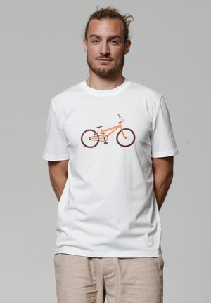 T-shirt en coton blanc avec un graphisme d'un vélo orange aux roues et accents marron, affiché sur un fond neutre.