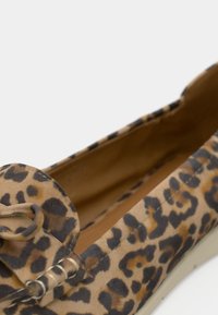Chaussure plate à imprimé léopard avec une tige en tissu doux, bout rond, détail en nœud et doublure intérieure beige. Couture détaillée sur l'extérieur.