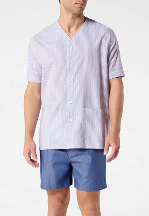 Uomo che indossa una camicia a righe a maniche corte, abbottonata, con due tasche anteriori, abbinata a pantaloncini blu tinta unita su sfondo semplice.