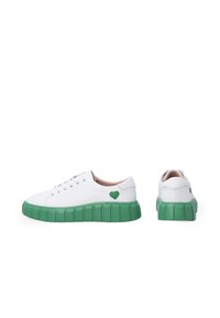 Weiße Sneaker mit einer strukturierten grünen Sohle, die auf der Seite mit einem grünen Herzakzent verziert sind. Schnürverschluss und Obermaterial aus glattem Leder.