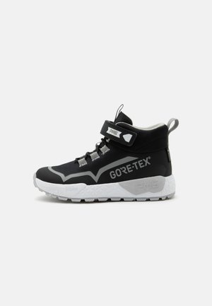Zapatilla alta negra y gris con suela blanca, tira de Velcro, cordones, marca Gore-Tex y tira en el talón para facilitar el calzado.