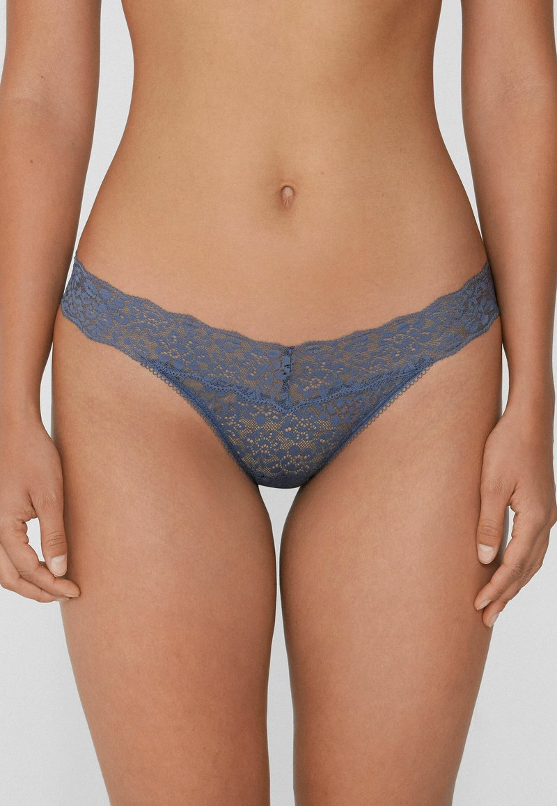 Blaue Spitzen-Slips mit Floral-Muster, weichem Material und einer gewellten Taille. Das Design bietet minimalen Schutz mit einem tief sitzenden Schnitt.