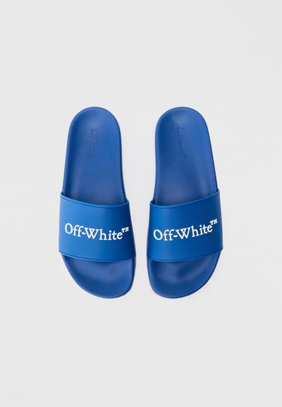 Kék csúszdás szandál, gumiból készült felsőrésszel, melyen fehér színnel van nyomtatva az "Off-White" felirat. Simább textúra, nyitott orr és lapos talp jellemzi.