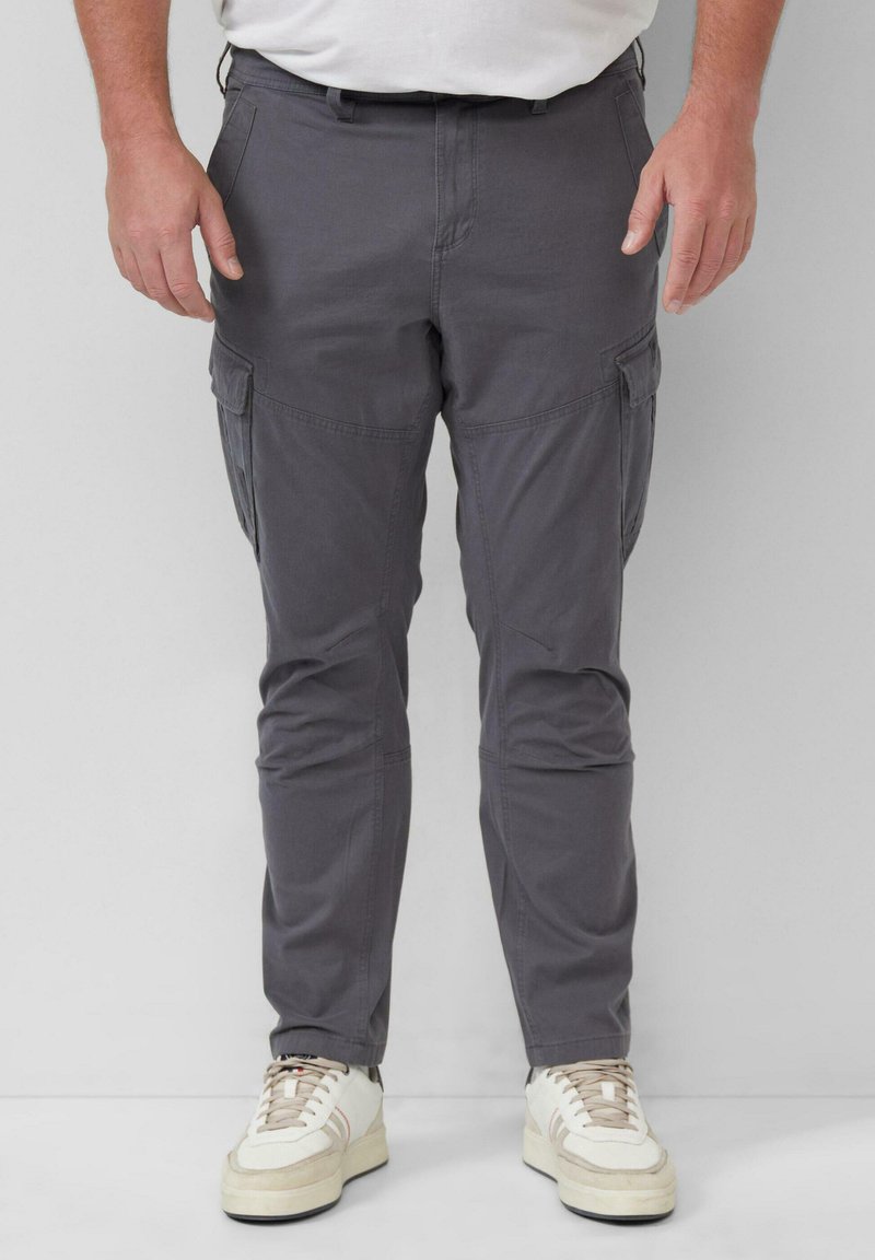 Grijze cargobroek met meerdere zijzakken, taps toelopende pasvorm en een lichtgewicht stof, gecombineerd met witte en beige sneakers.