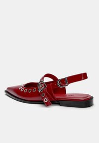 Rote Lackleder Slingback-Schuh mit spitzem Zeh, Ausschnitt-Design, silbernen Ösen und verstellbarem Knöchelriemen. Flache schwarze Sohle.