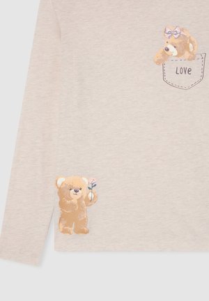 Maglietta a maniche lunghe di un beige chiaro con grafiche di orsetti dei cartoni; un orsetto con un fiocco in una tasca etichettata "Amore" e un altro con un fiore rosa.