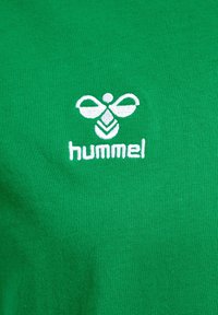 Grøn bomulds-T-shirt med hvidt broderet logo med bimdesign og "hummel" tekst. Glat tekstur med tætsiddende pasform.