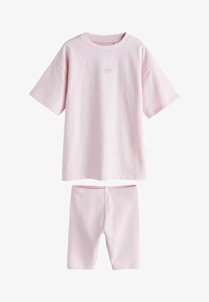 Tricou roz pal cu mâneci scurte, supradimensionat, cu text mic pe piept și pantaloni scurți de biciclist asortați, strâmți.