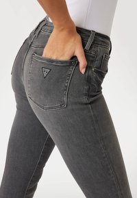 Grå denimjeans med en slimmad passform, med en triangulär logotypapplikation på bakfickan och en slät textur.
