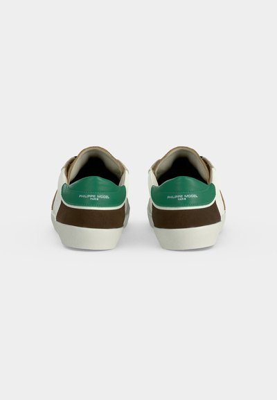 Paire de baskets vue de dos, avec des languettes vertes au talon portant le texte "Philippe Model Paris", des côtés marron et des semelles blanches.