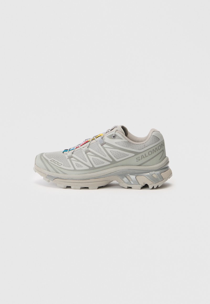 Shoe atlético cinza-claro com um superior em malha texturizada, detalhes reflexivos, sola de taxa distinta e atacadores coloridos. Apresenta um design de suporte.