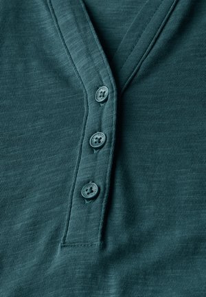 Teal v-neck shirt made of textured fabric, featuring a placket with four buttons in a contrasting shade, with horizontal ribbed pattern outlined.