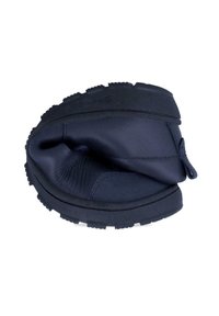 Zapato de cuero negro flexible doblado por la mitad, mostrando suela y material superior suaves y plegables sobre un fondo blanco.