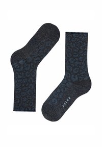 Een paar zwart-blauwe sokken met luipaardprint en metallic glans, waarvan de ene plat ligt en de andere rechtop staat, met "FALKE" branding.