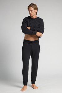 Svart långärmad topp med ribbad textur och rund halsringning, ihopparad med svarta joggers med dragsko, som har elastiska mudd och en slät finish.