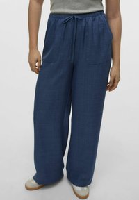 Wijdvallende broek van donkerblauwe stof, met een elastische tailleband met trekkoord, twee voorzakken en een gestructureerde afwerking.