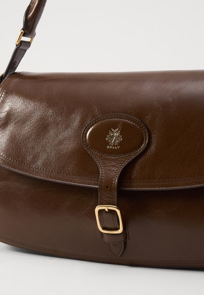 Brown leather shoulder bag featuring a curved flap, gold-tone hardware, and a logo accent on the front. Smooth texture with a glossy finish.
