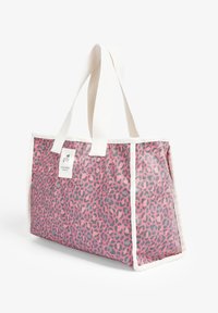Bolso tote rectangular con estampado de leopardo en tonos rosa y gris, asas y ribete de tela blanca, y una pequeña etiqueta con un logo de calavera en la parte frontal.