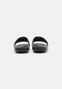Sandalias negras sin hebilla con diseño abierto en la parte trasera, fabricadas en material de goma, con perforaciones para transpirabilidad y suelas texturizadas.