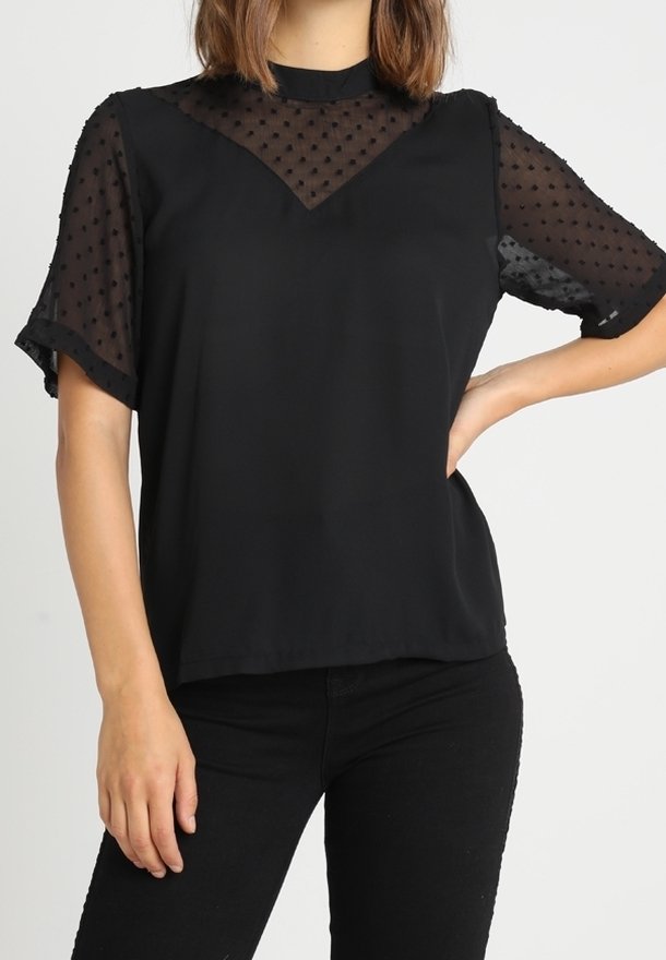 Blusa negra de manga corta con paneles de malla transparente de lunares en los hombros y el escote, con un ajuste relajado y cuello redondo.