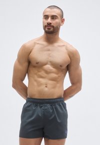 Γκρι μαγιό σορτς με ελαστική μέση και μικρό λογότυπο. Σχεδιασμένο για εφαρμοστή σιλουέτα, λεία υφή και ελαφρύ υλικό.