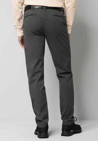 Graue Hose aus Baumwollmischung, schmales Schnitt, mit Gesäßtaschen und flachem Bund, kombiniert mit schwarzen Sportschuhen.