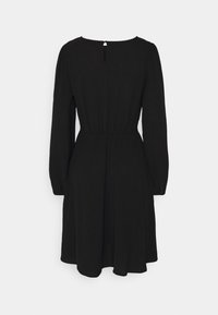 Robe noire avec des manches longues, une taille élastique et un détail en forme de clé au dos. Fabriquée dans un tissu doux, elle présente une jupe fluide.