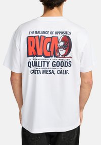 Camiseta blanca de algodón con un diseño gráfico colorido en la parte posterior, con texto en negrita y una representación de un criatura en estilo de dibujo animado.