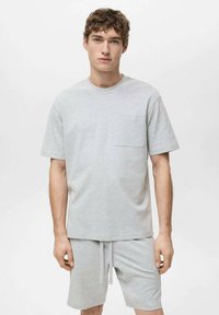 Lys grå bomulds t-shirt med rund halsudskæring og korte ærmer, med en brystlomme, parret med matchende shorts, der har elastisk talje.