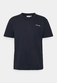 Czarny t-shirt z krótkim rękawem i okrągłym dekoltem, z małym białym logo "Calvin Klein" na lewej piersi, zaprezentowany na jednolitym tle.