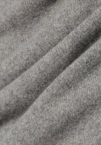 Hellgrauer gestrickter Stoff mit einer weichen Textur; weist subtile Farbvariationen und ein feines Rippenmuster auf.