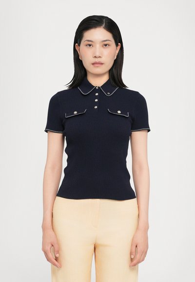 Marine ribbelpoloshirt met korte mouwen, witte afwerking, een knoopsluiting en twee voorzakken met knoopaccenten.
