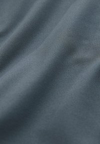 Teksturowana tkanina w głębokim niebieskim odcieniu o gładkim wykończeniu, prezentująca subtelny wzór drobnych linii na powierzchni.