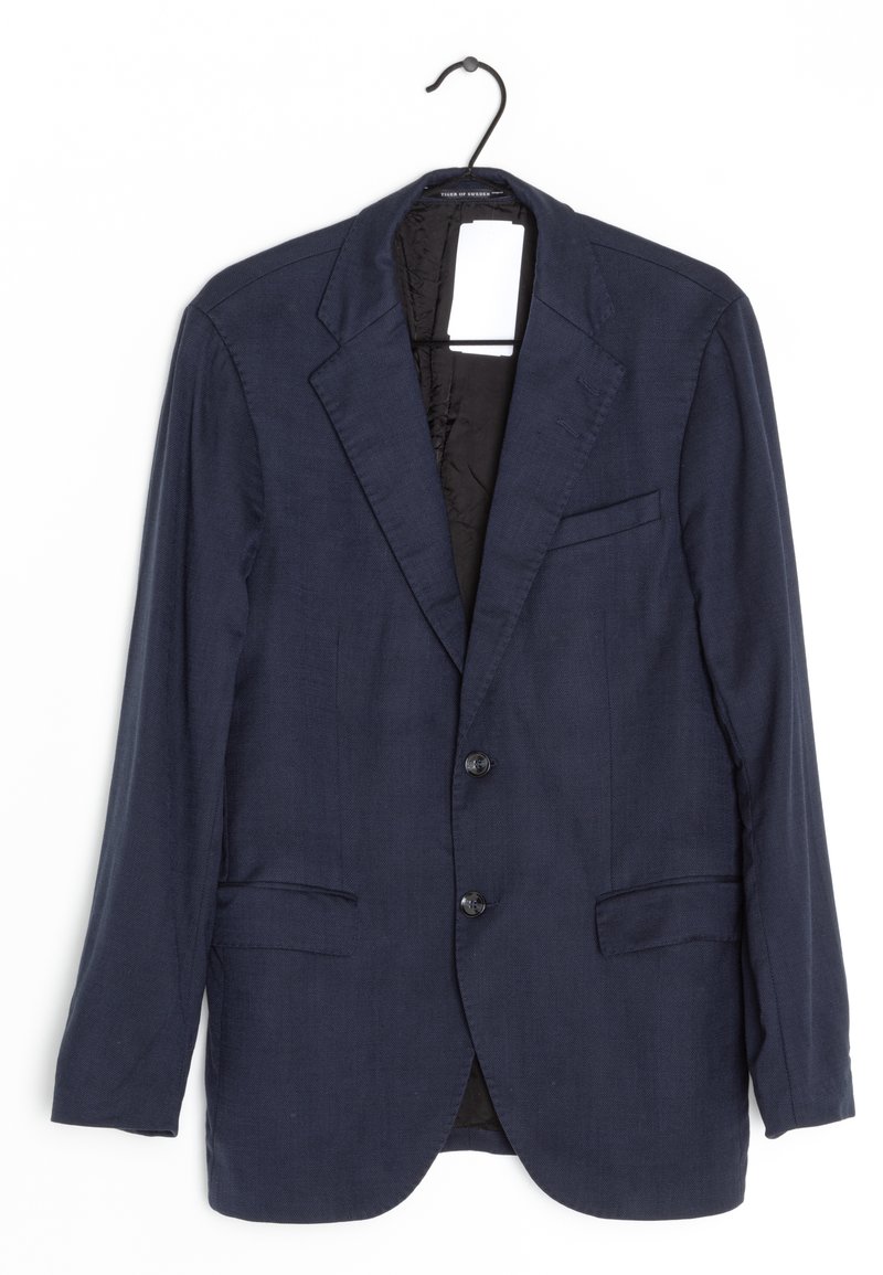 Blazer blu navy realizzato in tessuto testurizzato. Presenta una chiusura a due bottoni, rever a punta e due tasche anteriori. Appeso a un gancio nero.