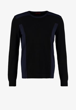 Pull noir avec des panneaux latéraux bleu foncé, col rond et poignets côtelés, associé à un jean noir slim et des chaussures de sport noires.