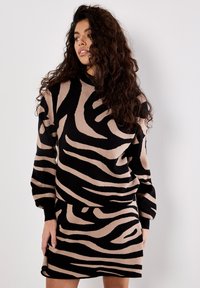Long-sleeve dress featuring a black and beige zebra stripe pattern, made from soft fabric, with a relaxed fit and ribbed cuffs.