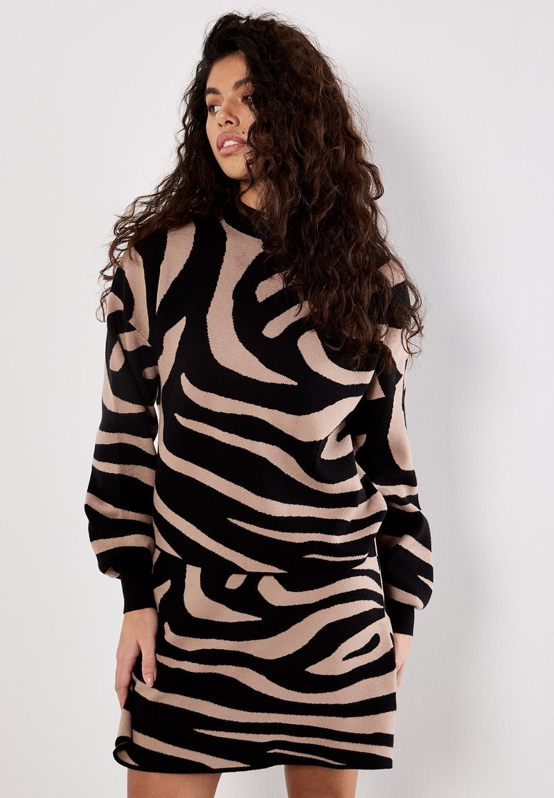 Long-sleeve dress featuring a black and beige zebra stripe pattern, made from soft fabric, with a relaxed fit and ribbed cuffs.