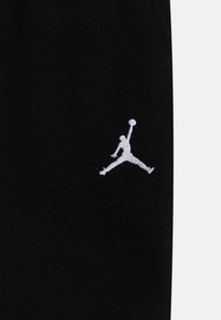 Svarta joggbyxor i bomull med en framträdande vit broderad Jumpman-logga på vänster lår.