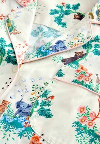 Kinder pyjama-top in crèmekleur met een print van bosdieren waaronder beren, olifanten, vossen en vogels, en roze bloemenaccenten.